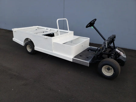 Custom fabricated white utility golf cart with flatbed and stake pockets, featuring STAKEBED POCKETS FOR 6 FT FLATBED DECK CONVERSION for enhanced cargo carrying capacity.