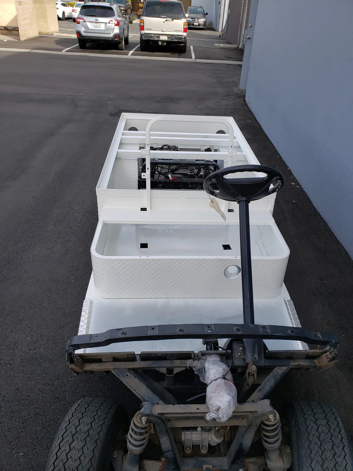 White flatbed cart with steel frame and steering wheel, showcasing YAM-DRIVE-ST-FLAT-72 YAMAHA DRIVE CART STRETCH INTO STEEL 6′ FLATBED, custom fabrication for golf carts.
