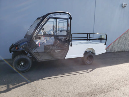 CUSH-800-ST-FLAT-72 CUSHMAN HAULER 800 CART STRETCHED INTO 6′ FLATBED with custom fabrication for golf carts, featuring a flatbed cargo area with railing and enclosed cabin.