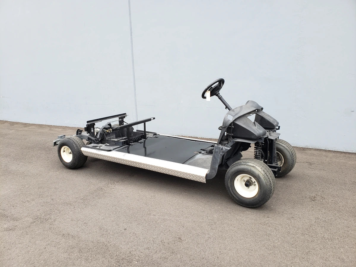 Bare golf cart frame with steering wheel and wheels, showcasing custom fabrication for golf carts in the EZGO-RXV-PS6-4F+2B EZGO RXV 6 PASSENGER CONVERSION.