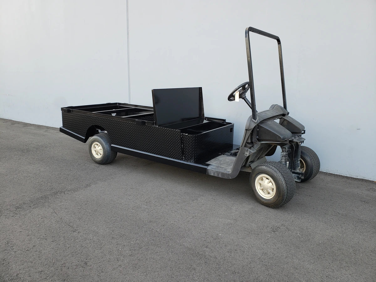 Black flatbed utility golf cart with custom storage box, designed for cargo and specialty use, featuring the EZGO-RXV-ST-FLAT-72 EZ GO RXV FLATBED RETROFIT CONVERSION for custom fabrication for golf carts.