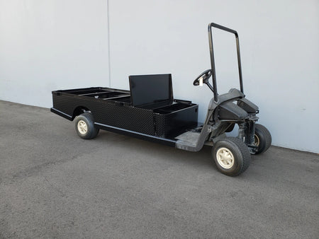 Black flatbed utility golf cart with custom storage box, designed for cargo and specialty use, featuring the EZGO-RXV-ST-FLAT-72 EZ GO RXV FLATBED RETROFIT CONVERSION for custom fabrication for golf carts.
