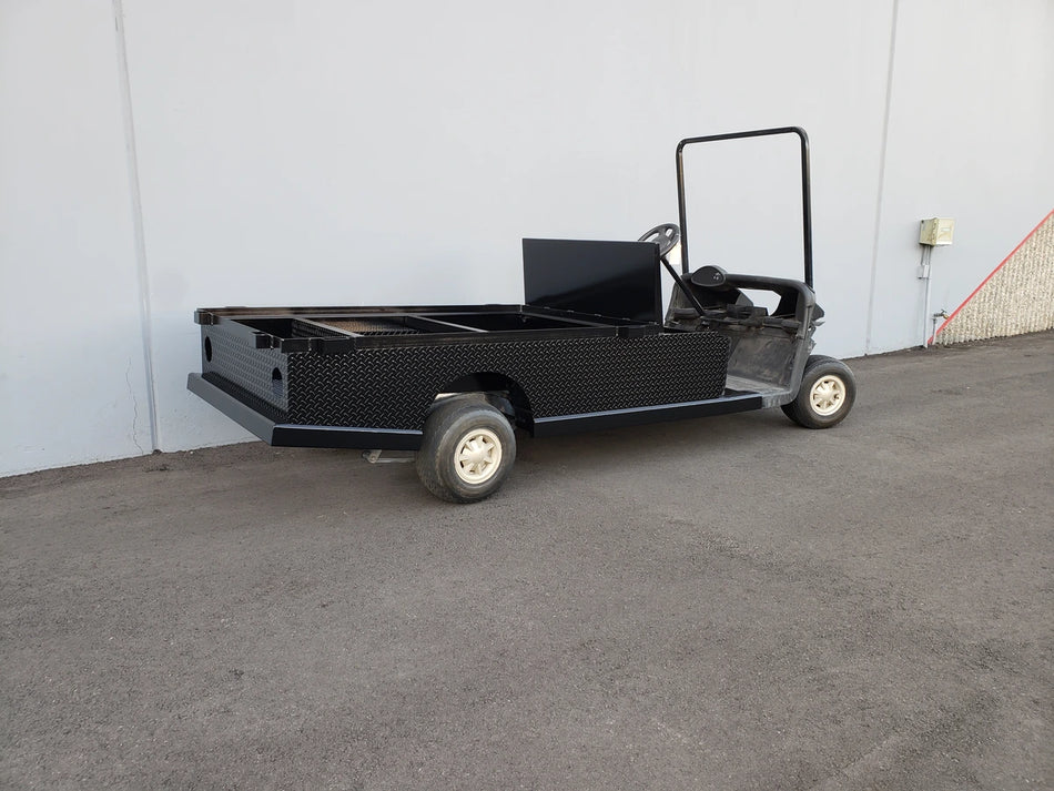 EZGO-RXV-ST-FLAT-72 EZ GO RXV FLATBED RETROFIT CONVERSION showing a custom-fabricated black flatbed attached to a golf cart for enhanced cargo utility and durability.