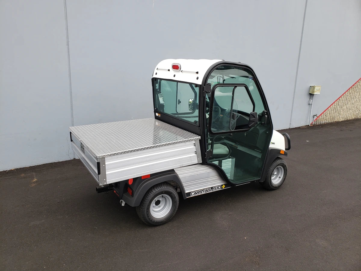 White and black utility golf cart with a flatbed cargo area designed for hauling, shown without the CC-510-UTILITYBOX-LID CLUB CAR 510 UTILITY BOX SOLID LOCKING LID RETROFIT installed.