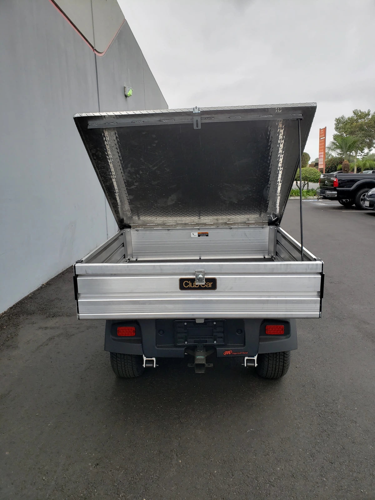 Rear view of a utility cart with the CC-510-UTILITYBOX-LID CLUB CAR 510 UTILITY BOX SOLID LOCKING LID RETROFIT open, showing a sturdy aluminum cargo bed designed for secure storage and transport.