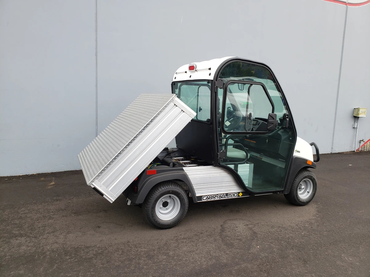 Small utility vehicle with a cargo bed tilted upward, featuring the CC-510-UTILITYBOX-LID CLUB CAR 510 UTILITY BOX SOLID LOCKING LID RETROFIT installed for secure storage and transport.