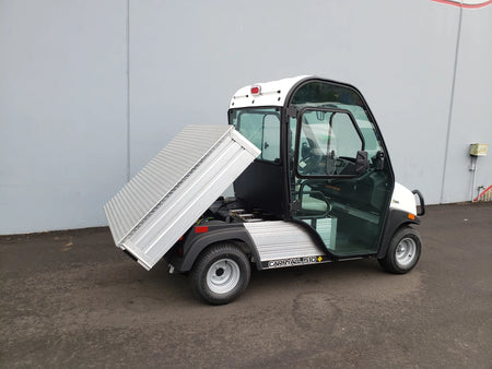 Small utility vehicle with a cargo bed tilted upward, featuring the CC-510-UTILITYBOX-LID CLUB CAR 510 UTILITY BOX SOLID LOCKING LID RETROFIT installed for secure storage and transport.