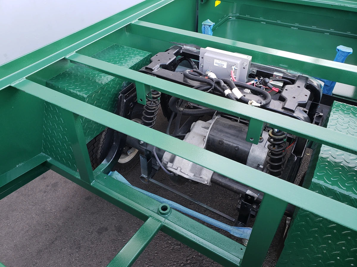Open frame close-up of green metal structure and suspension system showing custom fabrication for golf carts with EZGO-TXT-ST-FLAT-72 6 FT FLATBED CONVERSION FOR EZ GO TXT installed