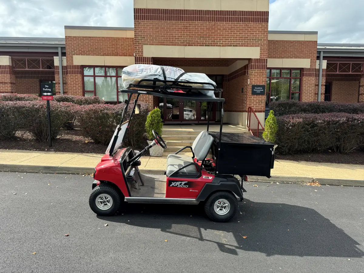 Red golf cart equipped with CC-PREC-50LRA CLUB CAR PRECEDENT ALUMINUM LADDER RACK carrying ladder and cargo box, showcasing custom fabrication for golf carts.