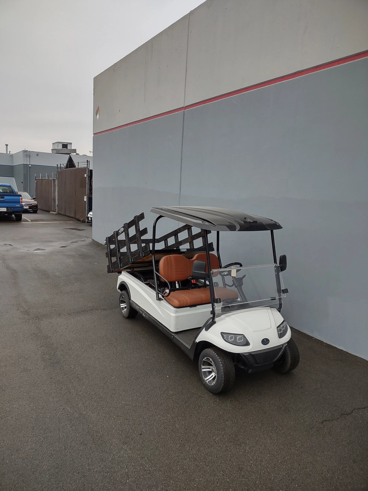 A golf cart fitted with the CRUISE-C20-DECK44X72-W WOOD FLATBED DECK showing custom fabrication for golf carts, featuring a wood flatbed with side rails ideal for cargo and utility transport.