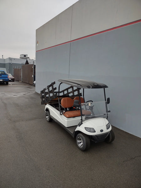 A golf cart fitted with the CRUISE-C20-DECK44X72-W WOOD FLATBED DECK showing custom fabrication for golf carts, featuring a wood flatbed with side rails ideal for cargo and utility transport.