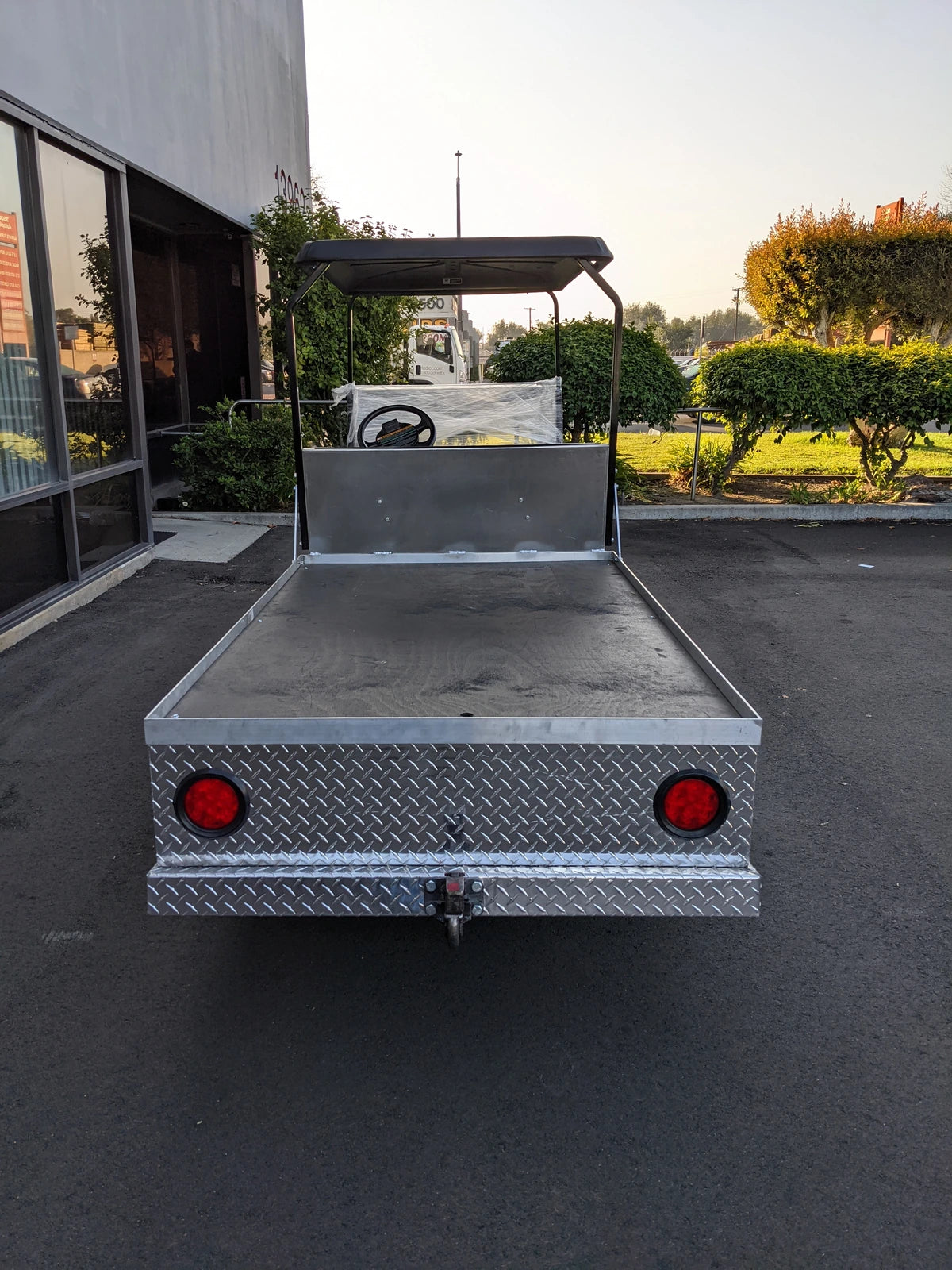 Rear view of a golf cart featuring the EZGO-TXT-AL-FLAT-72 6 FOOT ALUMINUM BED FLATBED CONVERSION with a custom fabricated flatbed made of aluminum diamond plate for cargo and utility use.