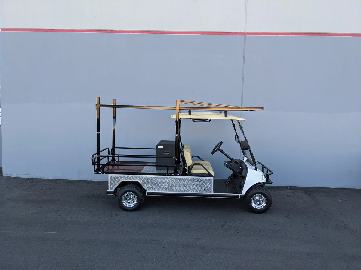 A golf cart equipped with an EVO-TURF-44X120-TLRI Top Mount Ladder Rack for mounting inside the bed of an Evolution Turfman 1000, featuring custom fabrication for golf carts.