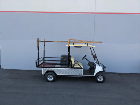 A golf cart equipped with an EVO-TURF-44X120-TLRI Top Mount Ladder Rack for mounting inside the bed of an Evolution Turfman 1000, featuring custom fabrication for golf carts.