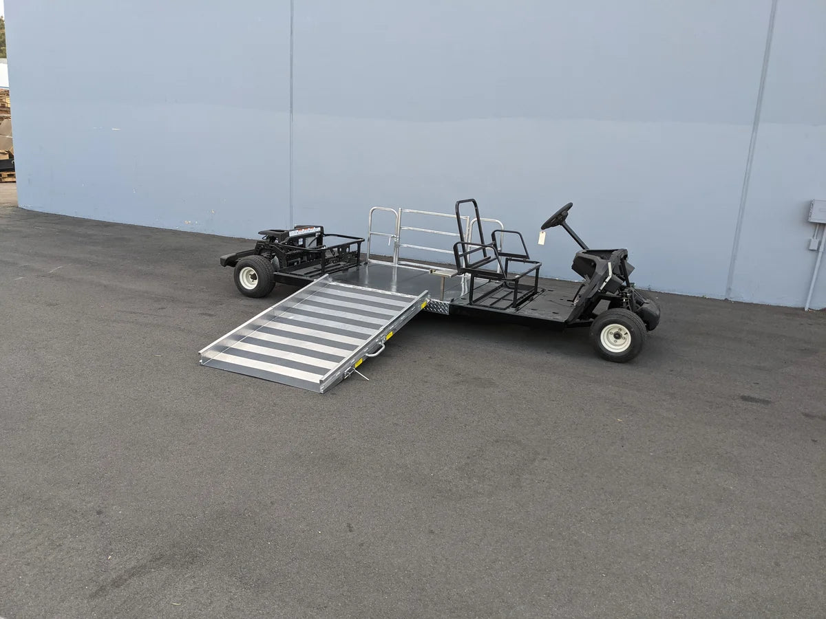 Golf cart with a ramp attached on a concrete surface against a light blue wall.