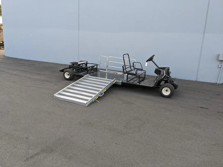 Golf cart with a ramp attached on a concrete surface against a light blue wall.