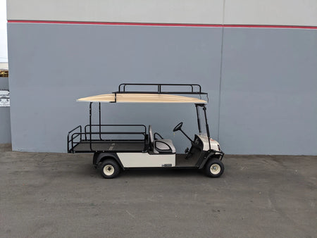 White golf cart equipped with CUSH-SHUTTLE2-84LR CUSHMAN SHUTTLE 2 LADDER RACK custom fabricated for golf carts, featuring a black metal ladder rack and cargo area.