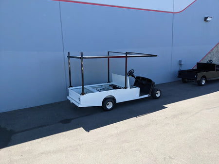White golf cart with FB-45X120-TLR FLATBED TOP LADDER RACK, 45″ X 120″ WITH REMOVABLE REAR CROSS BAR installed, custom fabricated for golf carts, ideal for hauling ladders and cargo.