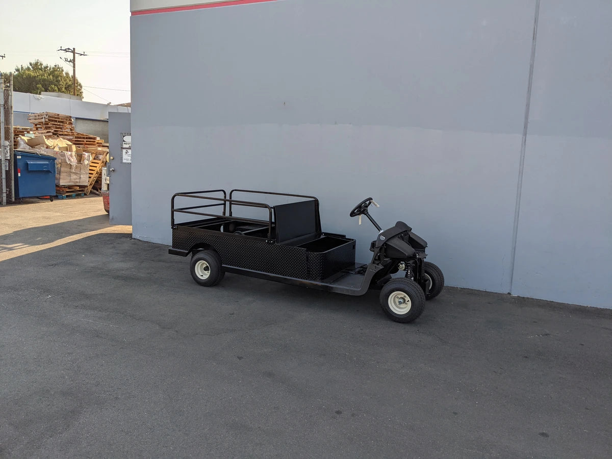 Black flatbed golf cart with metal railing and extended cargo area, custom fabricated for utility use, featuring EZGO-RXV-ST-FLAT-60 EZ GO RXV FLATBED RETROFIT CONVERSION