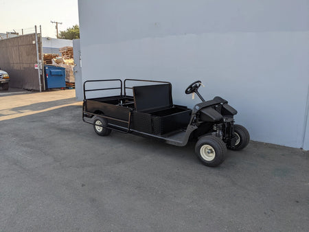 Black custom fabrication flatbed golf cart with cargo area and utility box parked outdoors featuring EZGO-RXV-ST-FLAT-60 EZ GO RXV FLATBED RETROFIT CONVERSION
