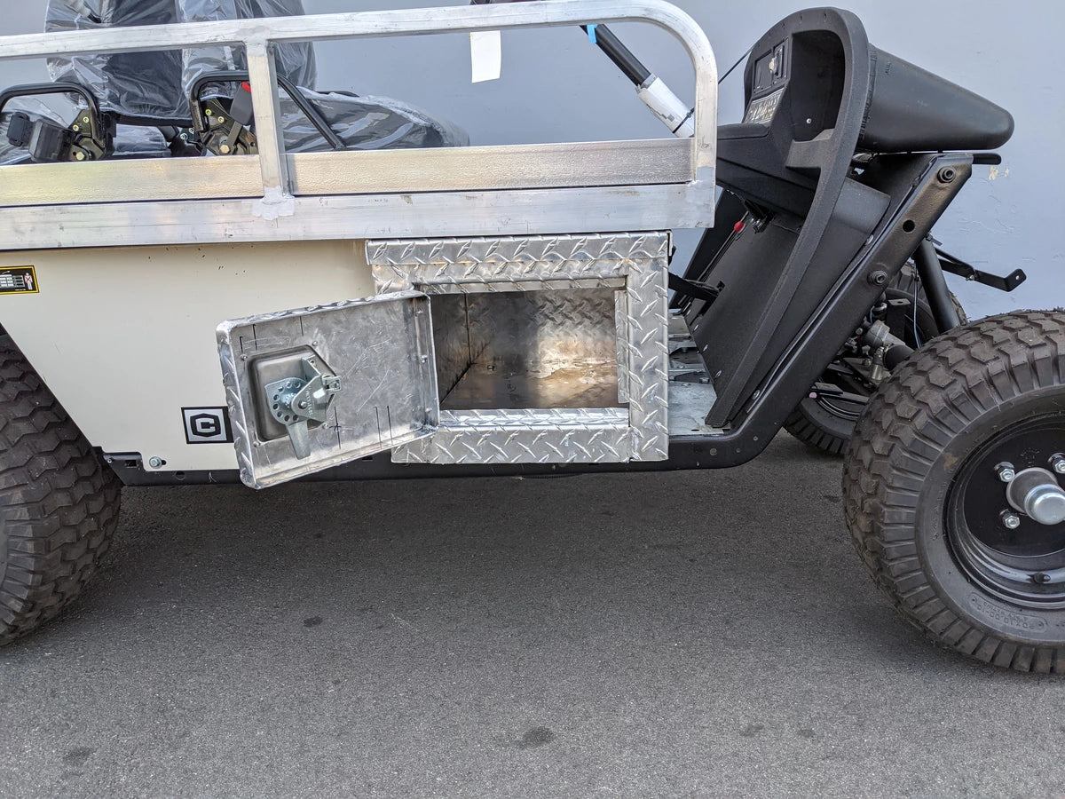 Custom fabricated aluminum storage compartment open on the side of a golf cart with rugged tires, part of the EZGO-EMT-84X24 EMT GOLF CART BED CONVERSION FOR EZ GO TXT GOLF CART.