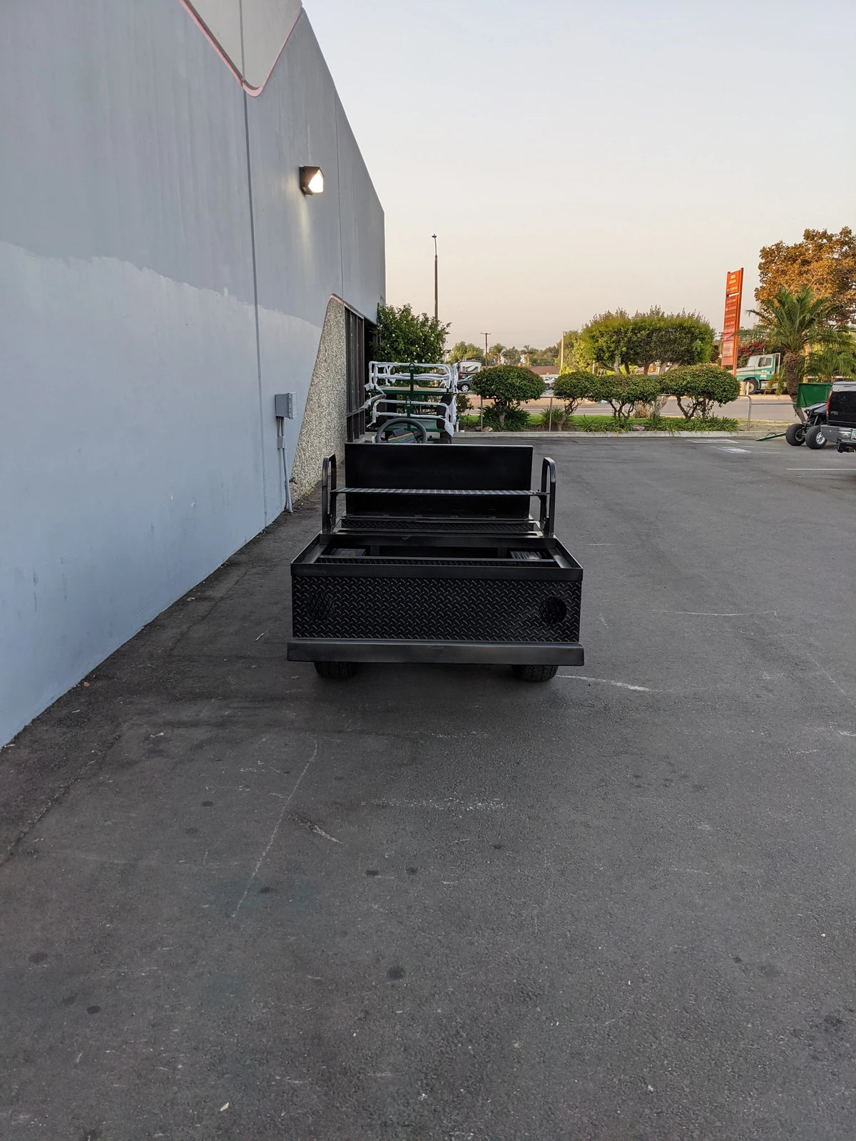 EZGO-RXV-ST-FLAT-CONV-72 EZ GO RXV FLATBED RETROFIT WITH CONVERTIBLE SEAT parked outside near a building, showcasing custom fabrication for golf carts with flatbed and convertible seating features.