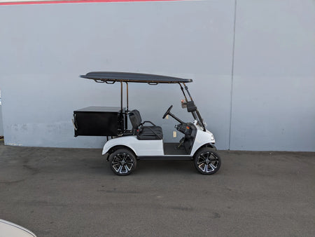 White golf cart equipped with EVO-CLASSIC-CARGO31 EVOLUTION CLASSIC LOCKING CARGO BOX mounted at the back, designed as a custom fabrication for golf carts, useful for cargo and utility purposes.