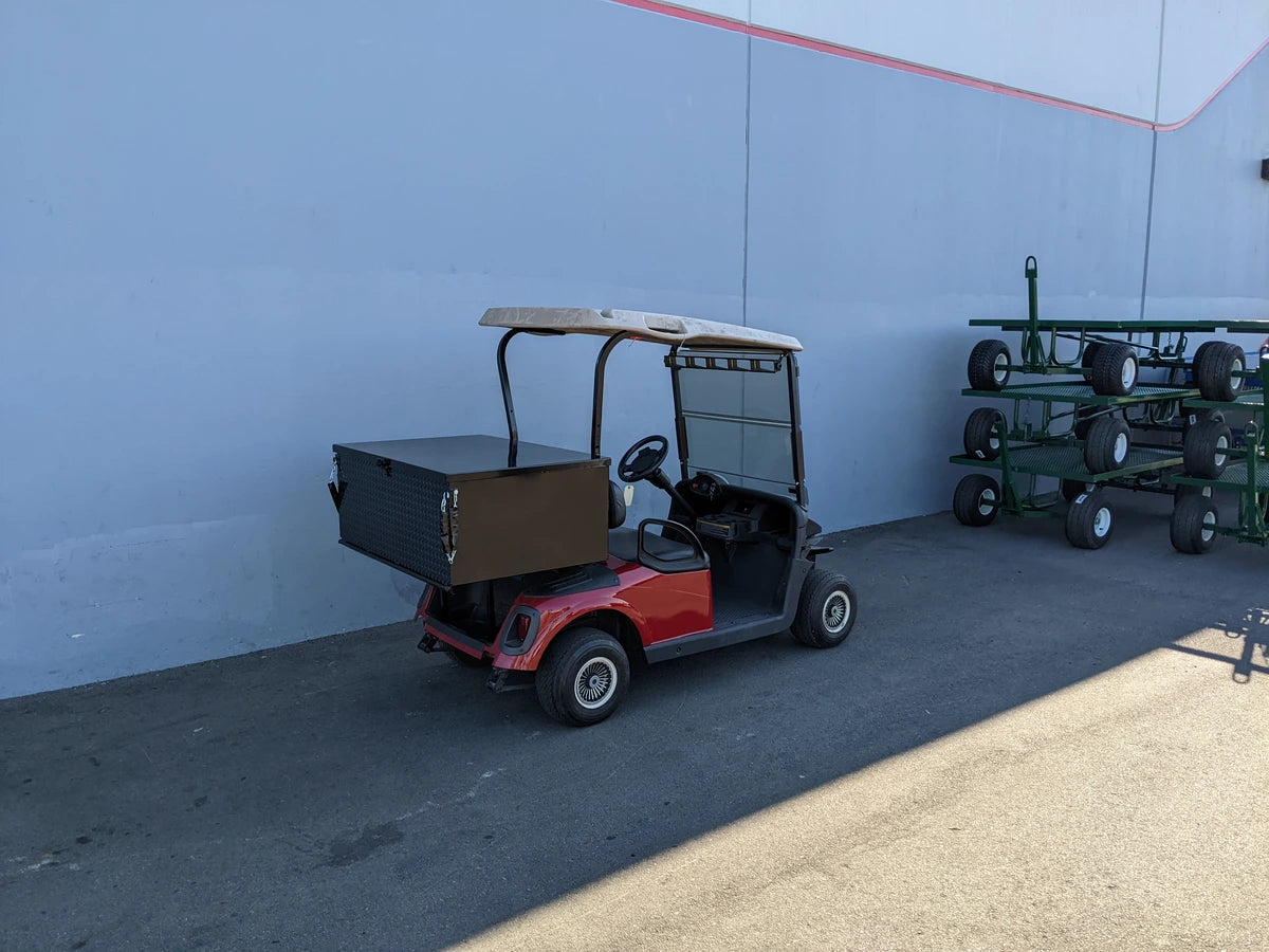 Red golf cart equipped with a custom-fabricated EZGO-RXV-CARGO31 EZ GO RXV HEAVY-DUTY LOCKING CARGO BOX utility box mounted at the rear for secure cargo storage.