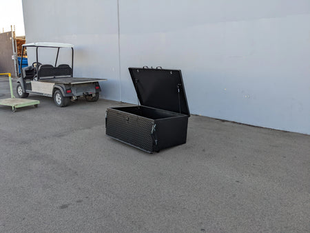 Black heavy duty locking cargo box with open lid designed for golf carts, shown beside a golf cart, custom fabrication for golf carts, CUSH-800-CARGO31-GS HEAVY DUTY LOCKING CARGO BOX FOR CUSHMAN 800 SERIES