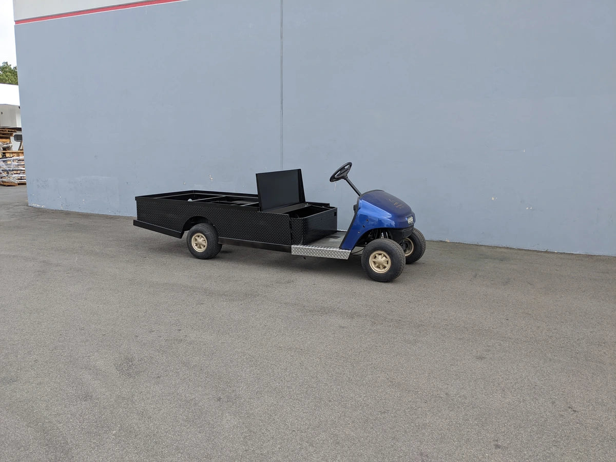 Golf cart with EZGO-TXT-ST-FLAT-72 6 FT FLATBED CONVERSION FOR EZ GO TXT featuring custom flatbed cargo area and utility box for specialized golf cart use.