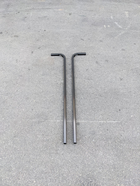 Two black metal bars with right-angle bends laid on a concrete surface, designed as CART-RTS GENERIC GOLF CART REAR TOP SUPPORT for golf cart accessories.