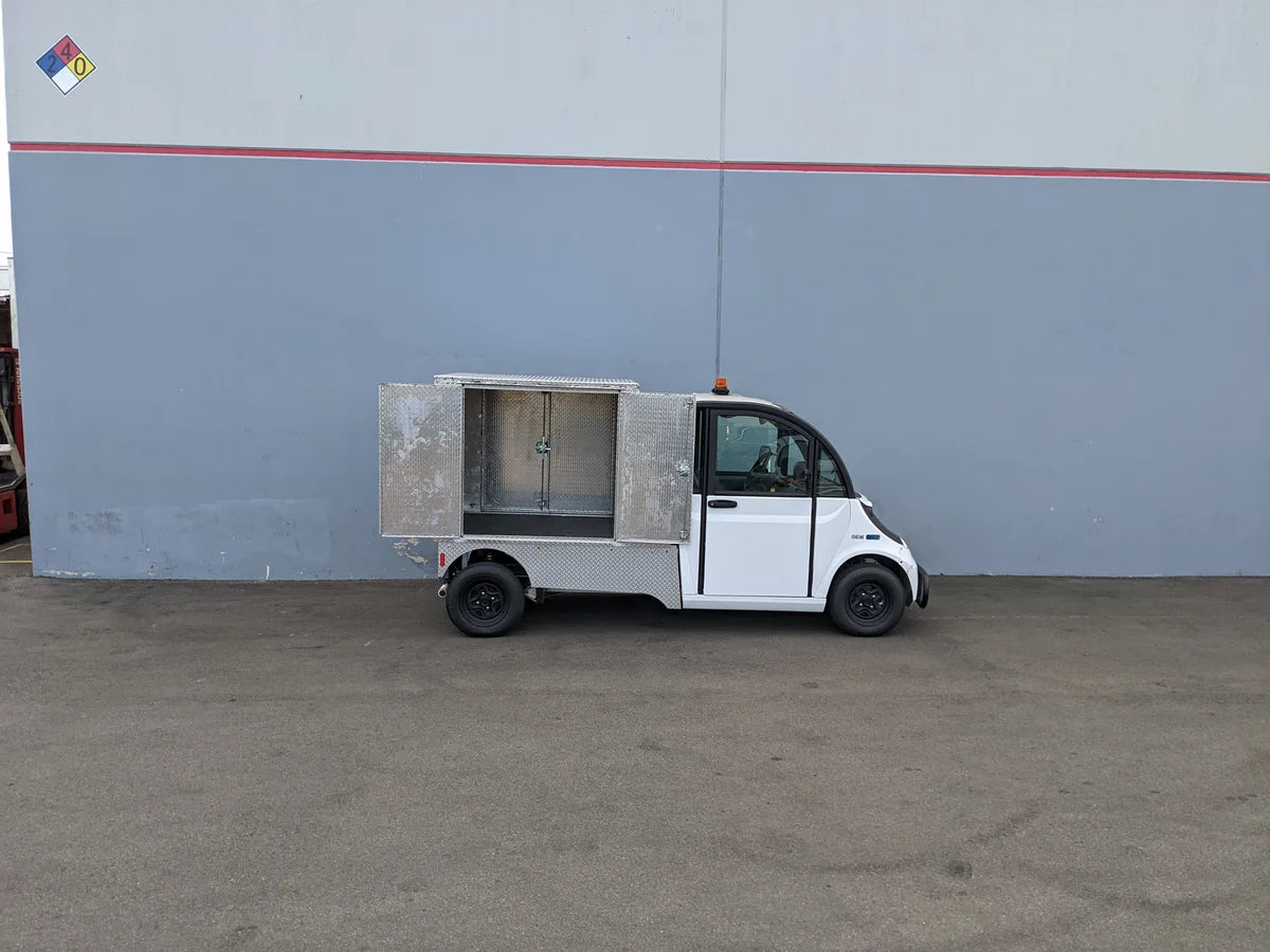Small utility vehicle equipped with the FMB-GEM-52X70X48-D-D2W0 Multi-Purpose Box for Flatbed, featuring custom fabrication for golf carts and ideal for cargo and utility storage.