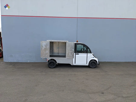 Small utility vehicle equipped with the FMB-GEM-52X70X48-D-D2W0 Multi-Purpose Box for Flatbed, featuring custom fabrication for golf carts and ideal for cargo and utility storage.