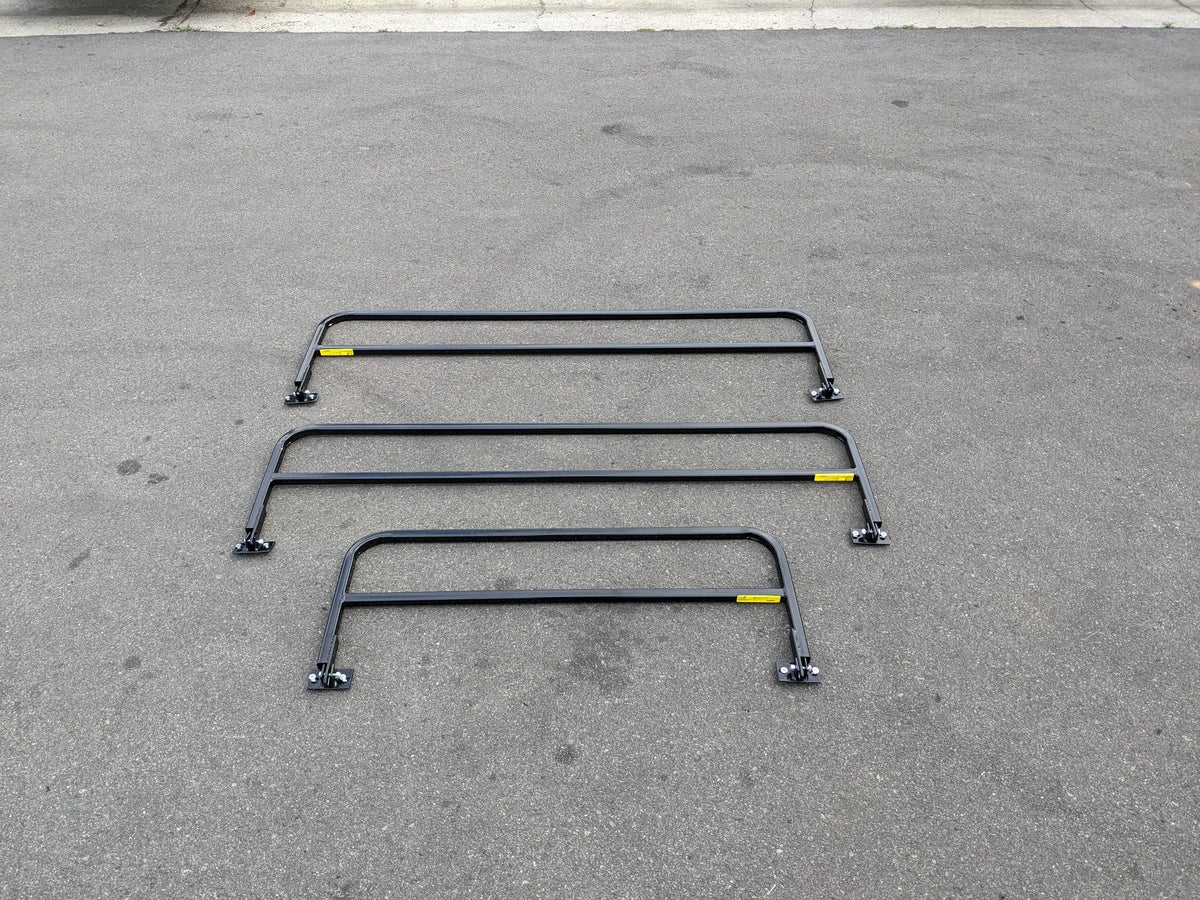 Three black metal rails laid out on asphalt surface showcasing DROP RAILS 48″ X 66″ X 18″ FOR 5-1/2 FT FLATBED CONVERSION designed for custom fabrication for golf carts.