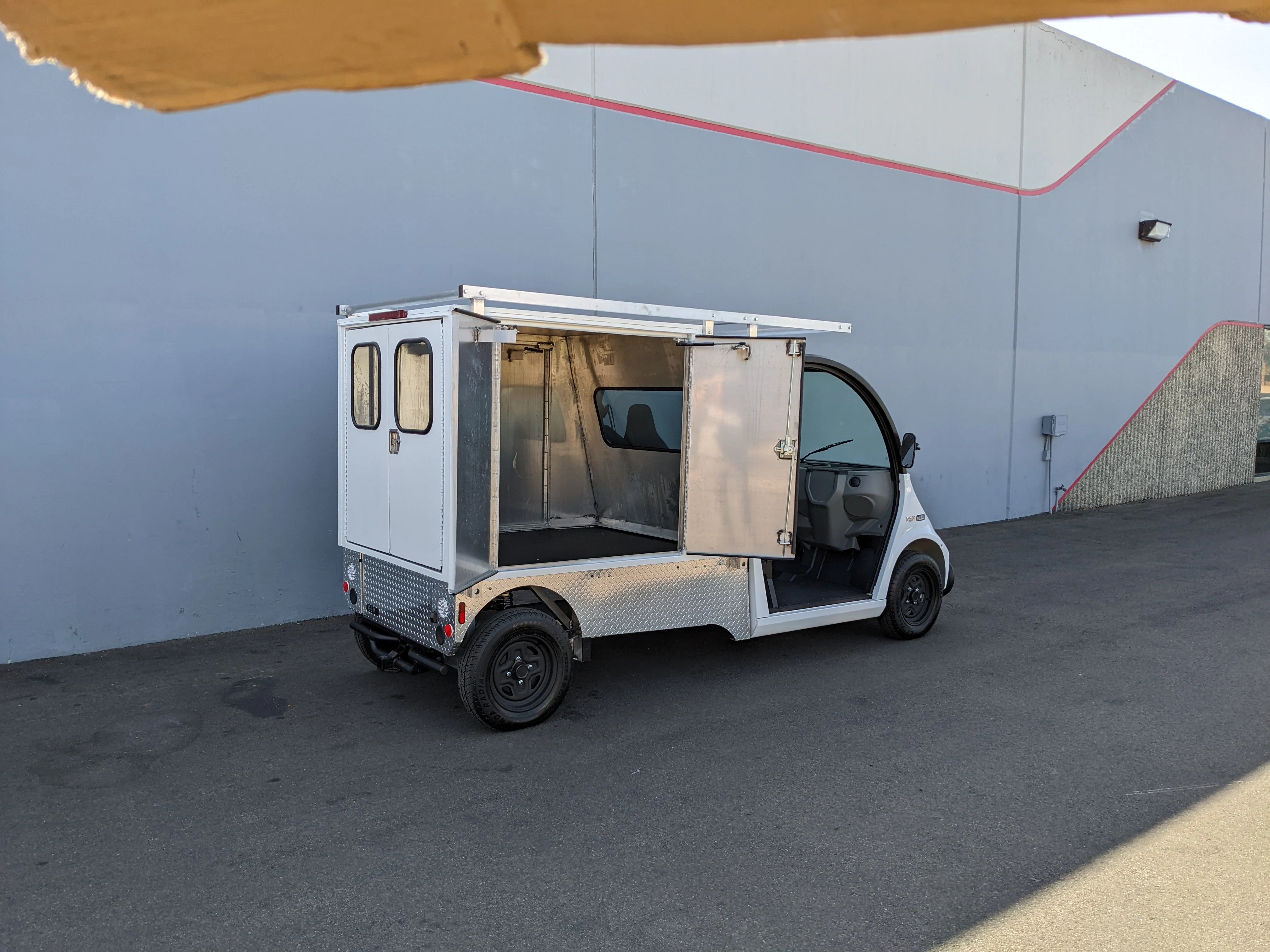 FMB-GEM-52X70X48-SL-D3W3 FLATBED ALUMINUM SMOOTH MULTI-PURPOSE LIGHT BOX FOR GEM ELXD 52″ WIDE X 70″ LONG X 48″ TALL WITH LOCKING DOORS mounted on a golf cart, custom fabrication for golf carts with utility cargo and locking doors.
