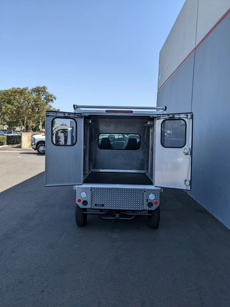 Rear view of an open FMB-GEM-52X70X48-SL-D3W3 FLATBED ALUMINUM SMOOTH MULTI-PURPOSE LIGHT BOX FOR GEM ELXD 52″ WIDE X 70″ LONG X 48″ TALL WITH LOCKING DOORS on a cart with custom fabrication for golf carts, showing smooth aluminum interior and locking doors.