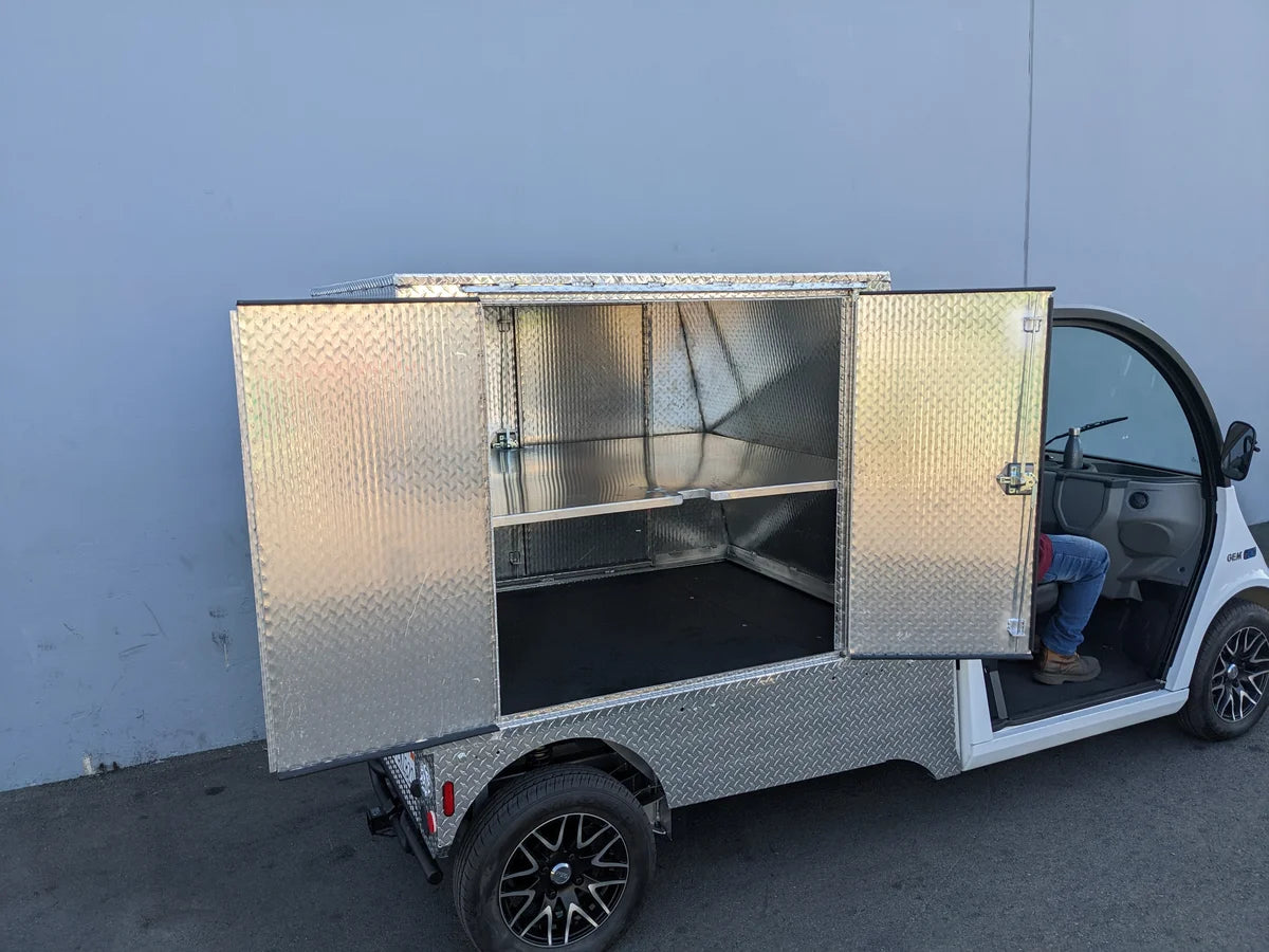 FMB-GEM-52X70X48-D-D2W0 Multi-Purpose Box for Flatbed mounted on a golf cart, featuring a diamond plate aluminum finish and open storage compartments, custom fabricated for golf carts.