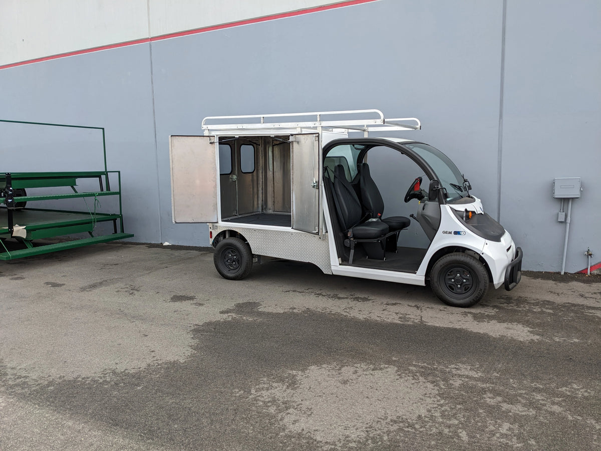FMB-GEM-52X70X48-SL-D3W3 FLATBED ALUMINUM SMOOTH MULTI-PURPOSE LIGHT BOX FOR GEM ELXD 52″ WIDE X 70″ LONG X 48″ TALL WITH LOCKING DOORS mounted on a small utility golf cart with custom fabrication for golf carts.