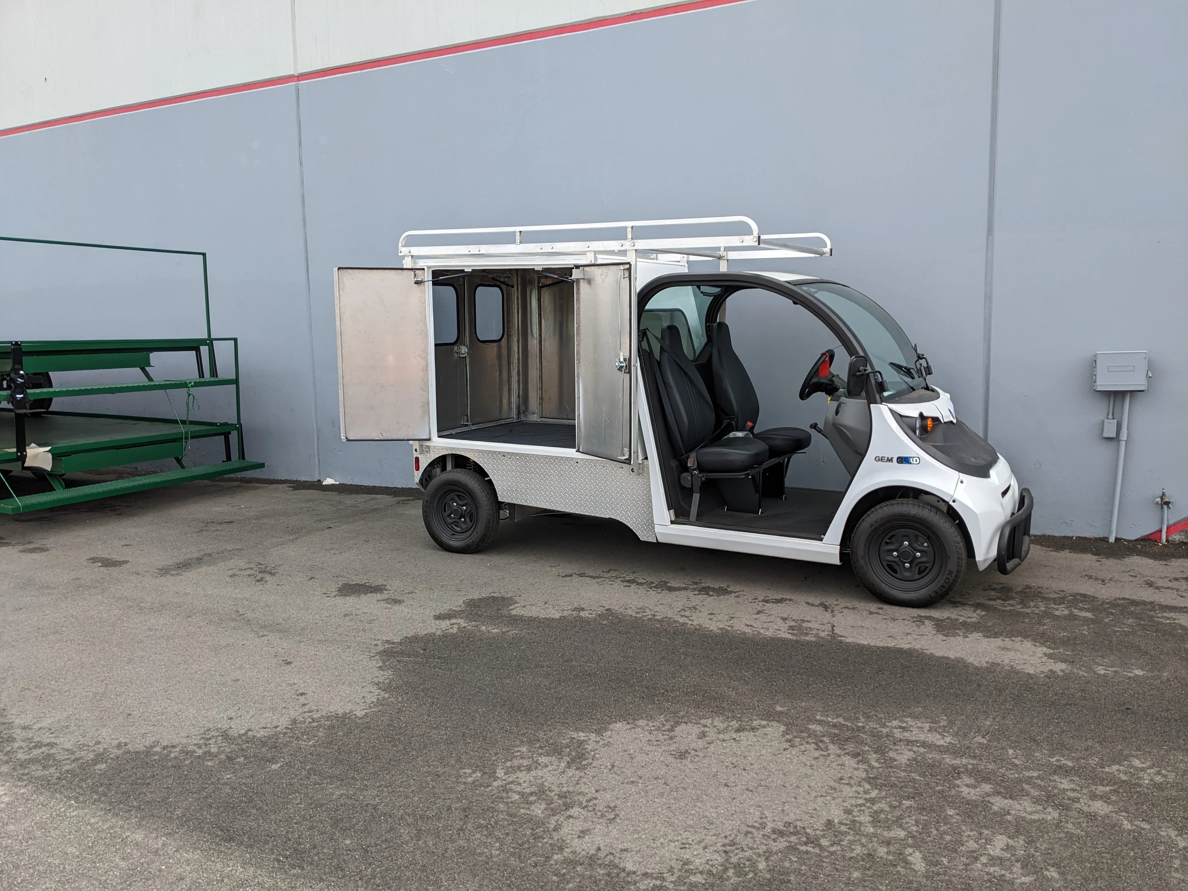 FMB-GEM-52X70X48-SL-D3W3 FLATBED ALUMINUM SMOOTH MULTI-PURPOSE LIGHT BOX FOR GEM ELXD 52″ WIDE X 70″ LONG X 48″ TALL WITH LOCKING DOORS mounted on a small utility golf cart with custom fabrication for golf carts.