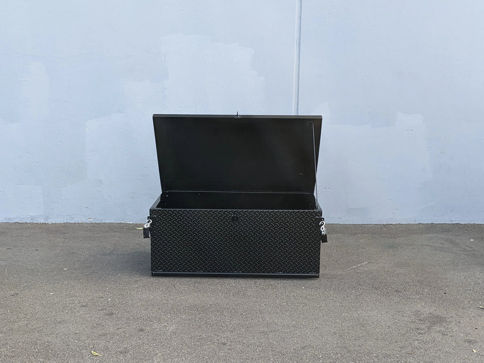 Black toolbox on a concrete floor with a light blue wall in the background