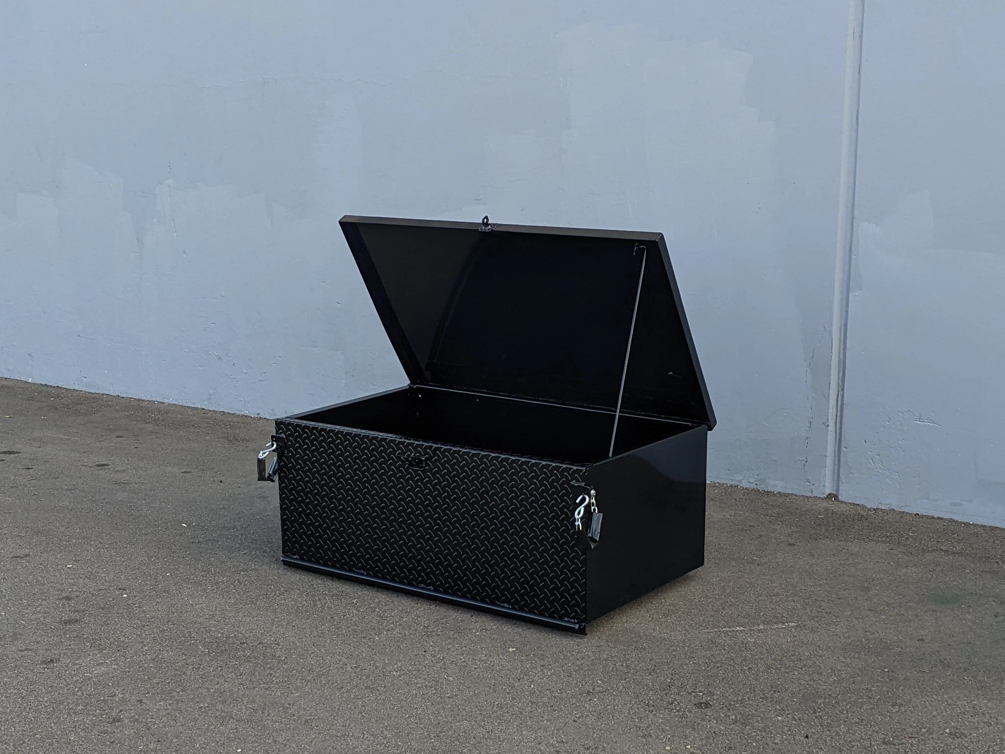 CARGO24-SKIDS CARGO BOX WITH LOCKING LID FOR DECK MOUNTING open black utility box with textured surface, designed for secure storage on flatbeds or golf carts.