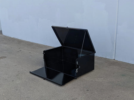 Black metal toolbox on a concrete floor with a light blue wall in the background
