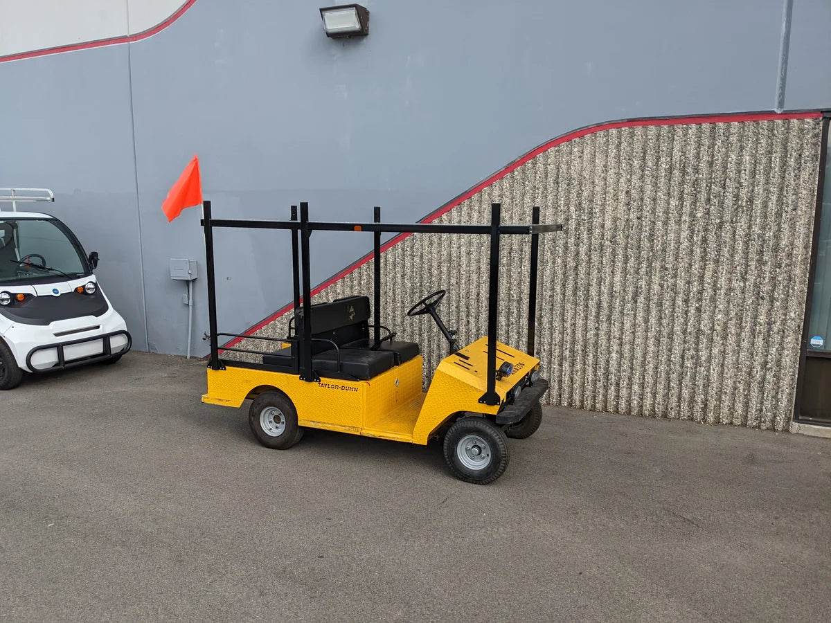 Yellow golf cart equipped with a TD-R380-44X96-TLR DECK top ladder rack with deck, featuring custom fabrication for golf carts and designed for carrying ladders and cargo efficiently.