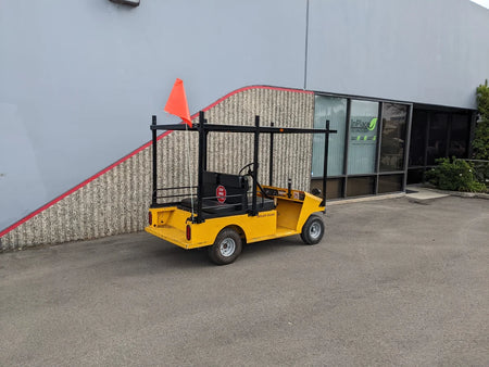Yellow golf cart equipped with a TD-R380-44X96-TLR DECK top ladder rack with deck, custom fabricated for golf carts, parked outside commercial building.