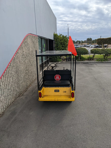 Rear view of a yellow golf cart featuring a TD-R380-44X96-TLR DECK top ladder rack with deck, equipped with a custom fabrication for golf carts and a visible safety flag.