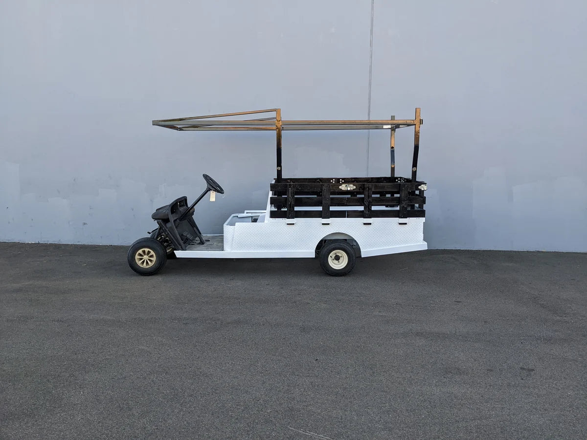 White flatbed golf cart equipped with custom-fabricated black STAKE-SIDES-44X72X18 Flatbed Golf Cart Stake Sides and steel frame for cargo and utility purposes.