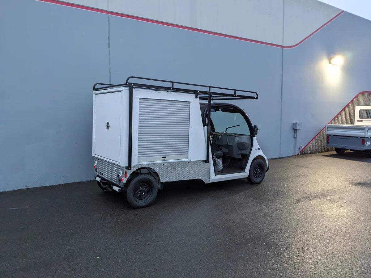White utility golf cart with FMB-GEM-52X70X48-S-D3W0 ROLL UP DOORS FLATBED ALUMINUM SMOOTH MULTI-PURPOSE BOX FOR GEM ELXD 52 WIDE X 70 LONG X 48 TALL, custom fabricated for golf carts.