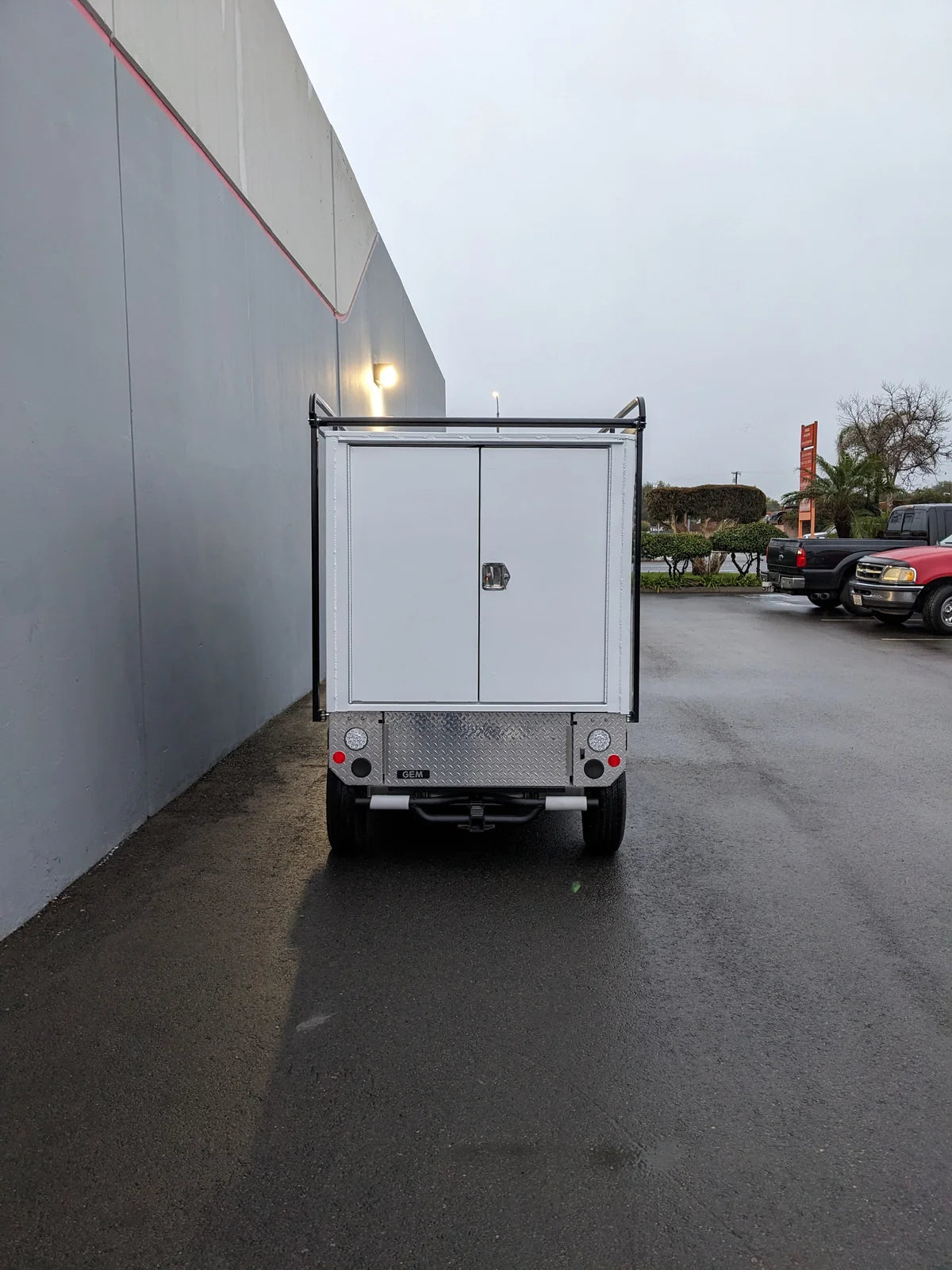 Rear view of a utility cart featuring the FMB-GEM-52X70X48-S-D3W0 ROLL UP DOORS FLATBED ALUMINUM SMOOTH MULTI-PURPOSE BOX FOR GEM ELXD 52 WIDE X 70 LONG X 48 TALL custom fabricated for golf carts.