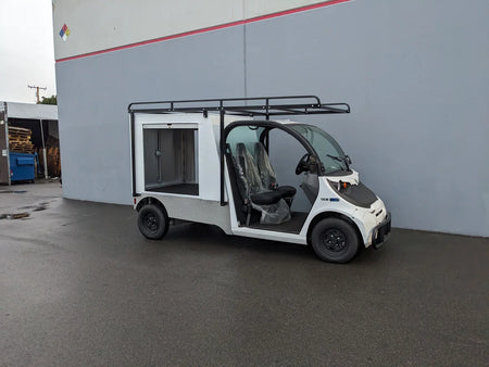 Small white utility golf cart with a custom multi-purpose aluminum box featuring FMB-GEM-52X70X48-S-D3W0 ROLL UP DOORS FLATBED ALUMINUM SMOOTH MULTI-PURPOSE BOX FOR GEM ELXD 52 WIDE X 70 LONG X 48 TALL, designed for custom fabrication for golf carts.