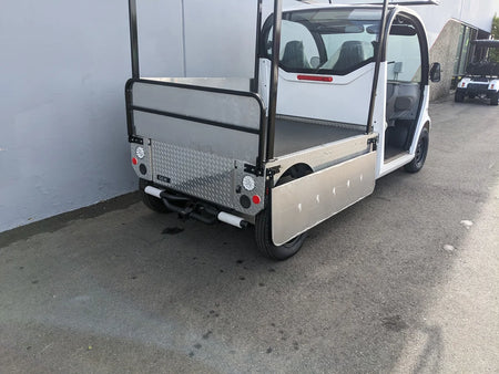 White golf cart with a flatbed and custom bed-mounted ladder rack, featuring metal side panels and a rear diamond plate section. GEM-ELXD-53X120-IN-TLR Top Mount Ladder Rack for mounting inside the bed of a GEM ELXD. Custom fabrication for golf carts.
